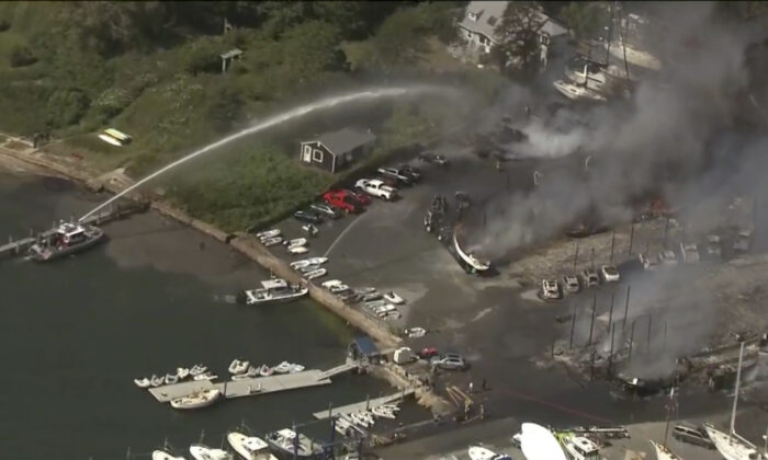 Crews battle a massive fire that has destroyed buildings, cars, and vessels at a boat yard in Mattapoisett, Mass., on Aug. 19, 2022. (WCVB via AP)