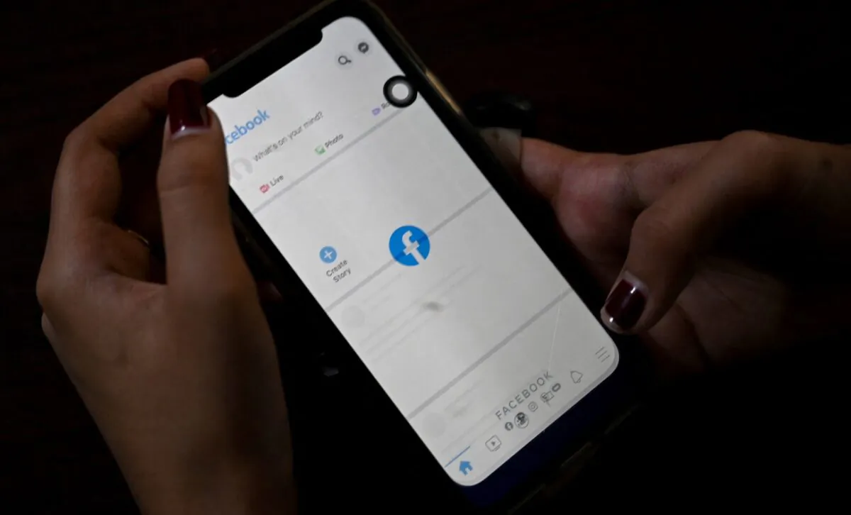 A woman uses her mobile phone to check Facebook. (STR/AFP via Getty Images)