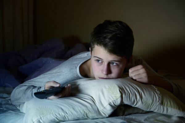 man watching tv in bed at night
