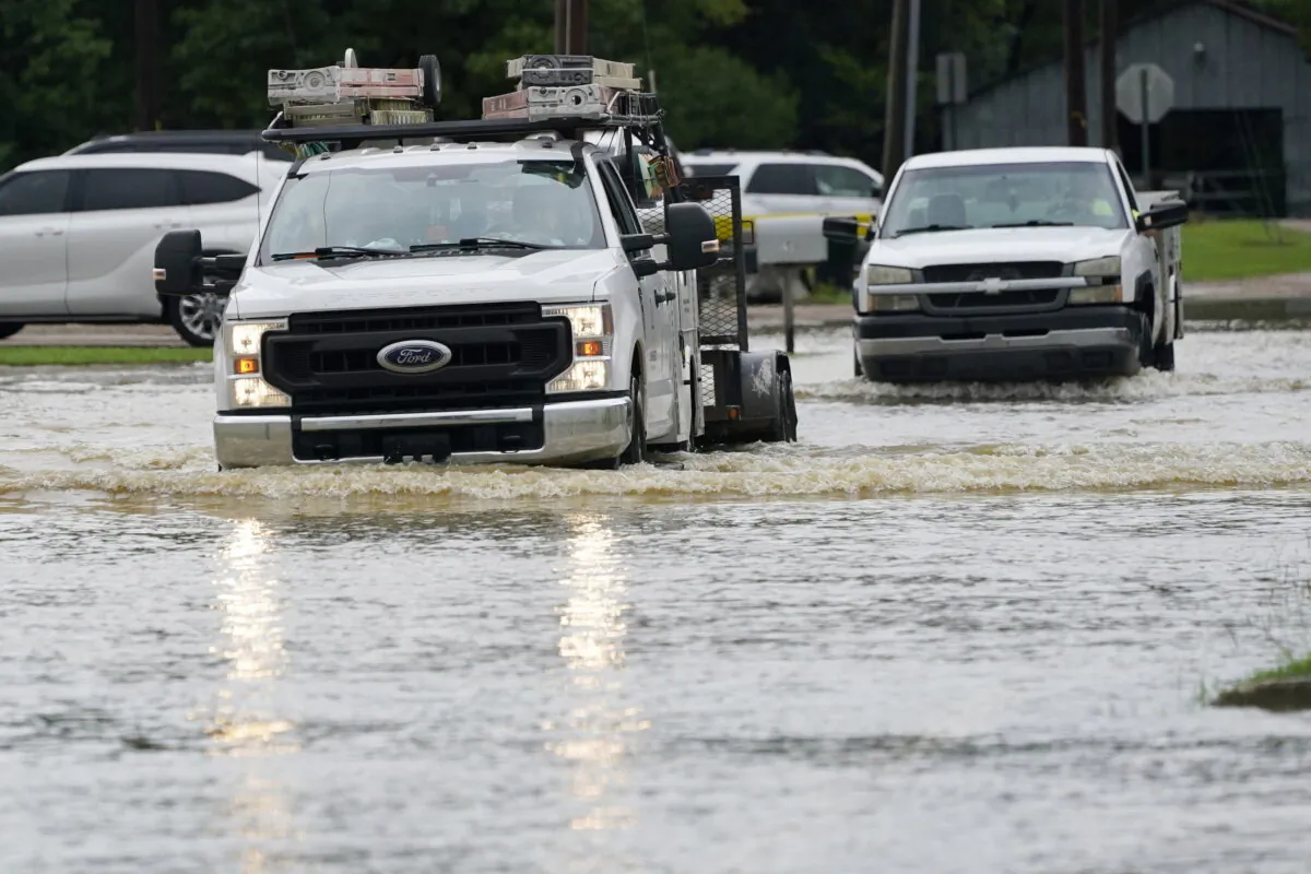 A couple of pickup trucks creep through flood waters in Richland, Miss., following a morning of torrential rains, on Aug. 24, 2022. (Rogelio V. Solis/AP Photo)