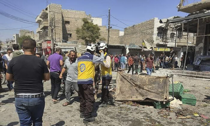 Syrian White Helmet civil defense workers (C) gather with civilians at the rocket attacked scene, at al-Bab town, north Syria, on Aug. 19, 2022. (Syrian Civil Defense White Helmets via AP)