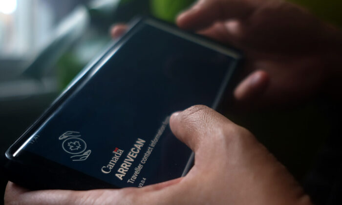 A person holds a smartphone set to the opening screen of the ArriveCan app, which requires people to declare their vaccination status to be able to enter Canada. (The Canadian Press/Giordano Ciampini)