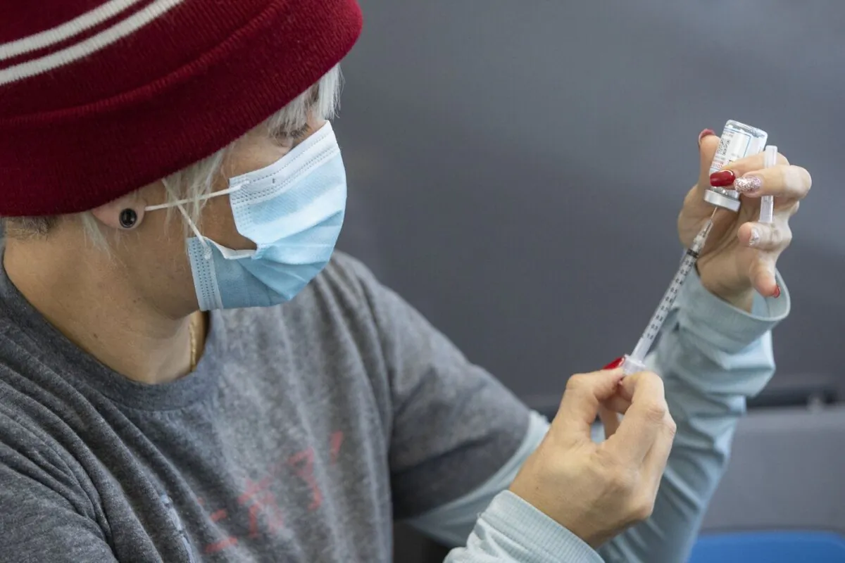 Clinic volunteer Kelly Brown draws out Moderna vaccine during a drive through COVID-19 vaccine clinic at St. Lawrence College in Kingston, Ont., on Jan. 2, 2022. (The Canadian Press/Lars Hagberg)
