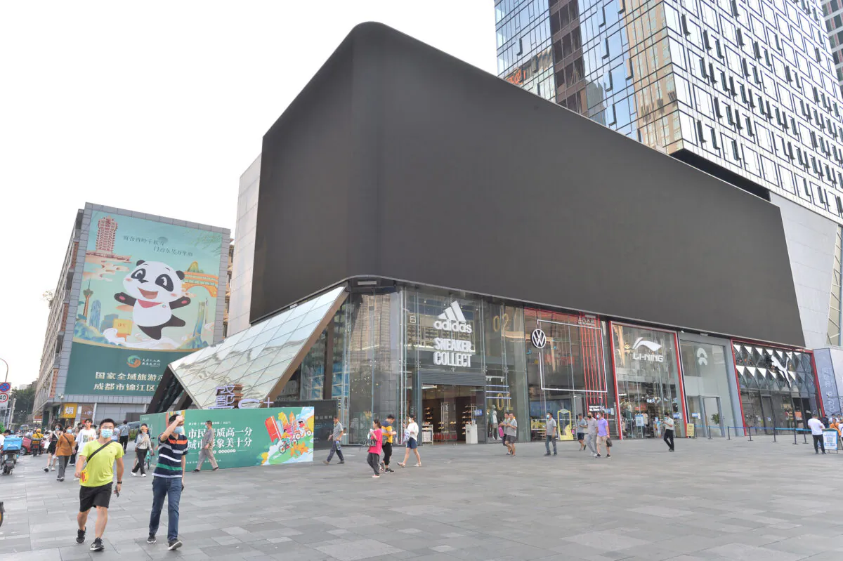 People walking past a screen, which is turned off to save energy, in Chengdu, in China's southwestern Sichuan Province, on Aug. 17, 2022. (STR/AFP via Getty Images)