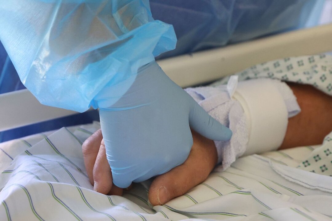 A doctor holds the hand of a patient. (Ronny Hartmann/AFP via Getty Images)