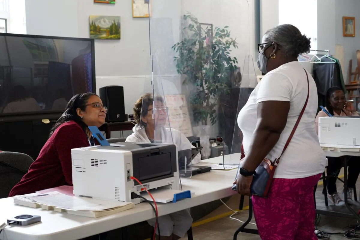 A voter talks with poll workers at Middletown Senior Center on primary day Aug. 23, 2022. (Cara Ding/The Epoch Times)