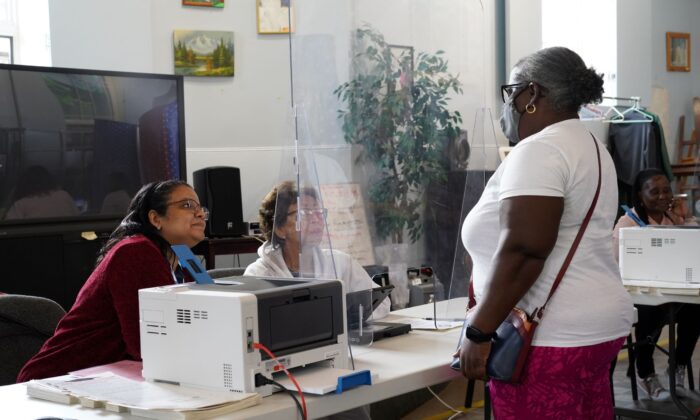 A voter talks with poll workers at Middletown Senior Center on primary day Aug. 23, 2022. (Cara Ding/The Epoch Times)