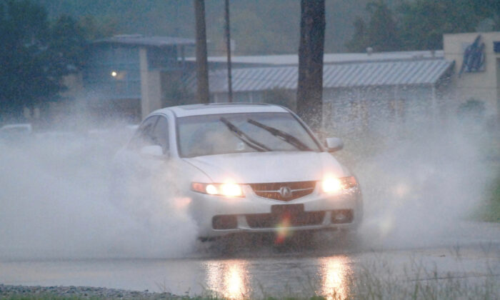 A driver drives through high water on Dale Drive in Marion, Miss., on Aug. 24, 2022. (D'Courtland Christian/The Meridian Star via AP)