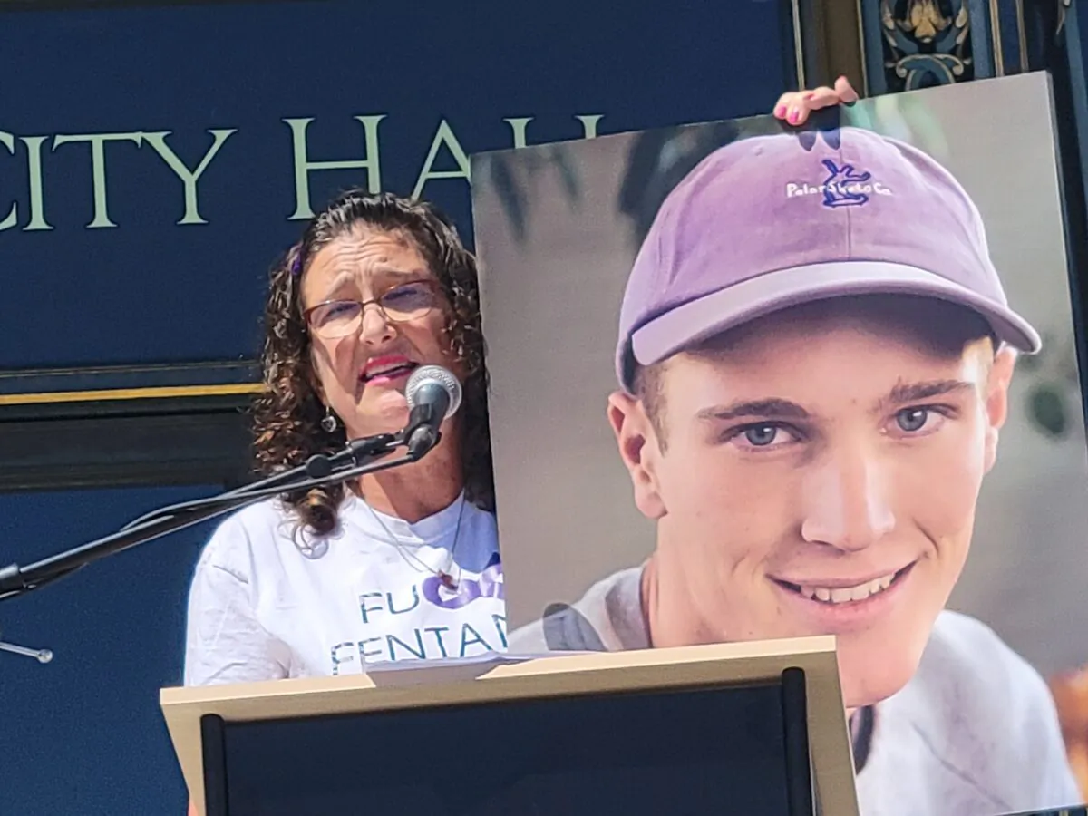 Michelle Leopold speaks at a rally in front of City Hall in San Francisco on Aug. 21, 2022, while holding a photo of her son Trevor who was a victim of fentanyl poisoning. (Jason Blair/NTD Television)