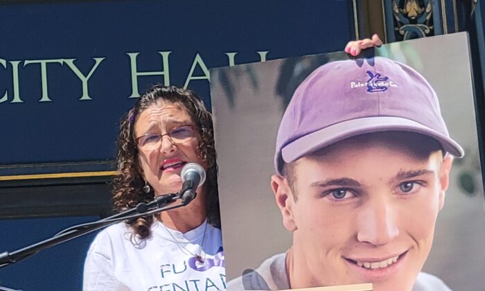 Michelle Leopold speaks at a rally in front of City Hall in San Francisco on Aug. 21, 2022, while holding a photo of her son Trevor who was a victim of fentanyl poisoning. (Jason Blair/Epoch Times)