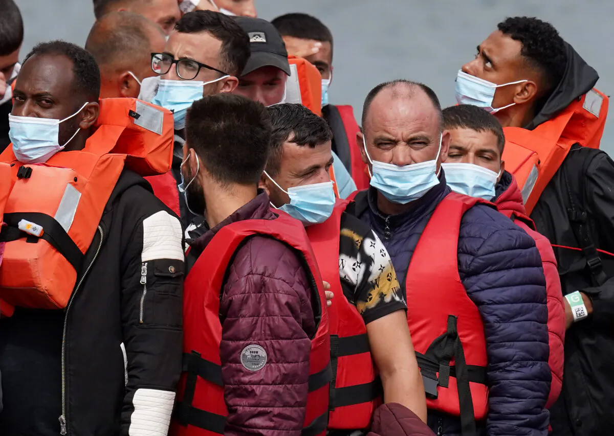 Illegal immigrants, whose small boat was intercepted in the English Channel, are escorted ashore from a Border Force vessel in Dover, Kent, on Aug. 23, 2022. (PA)