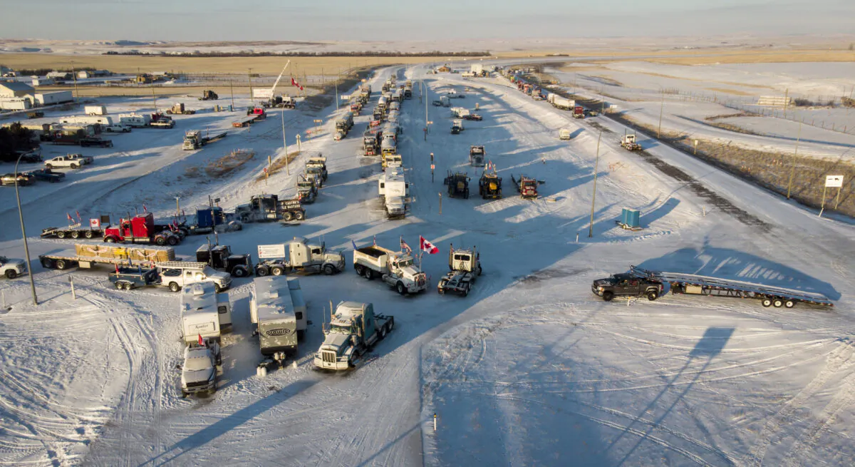 Protesters demonstrating against COVID-19 mandates gather as a truck convoy blocks the highway at the U.S. border crossing in Coutts, Alta., on Feb. 2, 2022. (The Canadian Press/Jeff McIntosh)