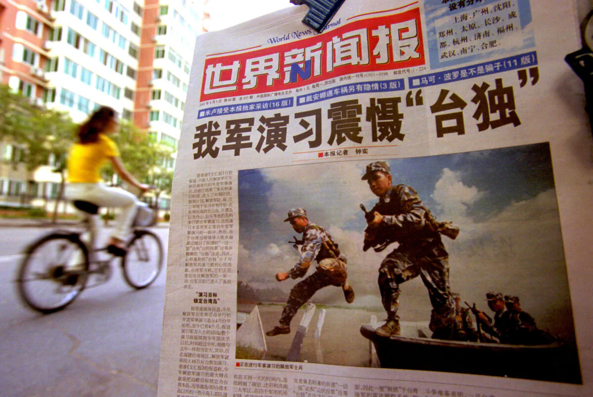 A Chinese cyclist rides by a newspaper with a front page photo featuring the People's Liberation Army (PLA) soldiers in military exercise with the headline "Chinese Military Exercise Frightens Pro-Independence" Aug. 7, 2002 in Beijing, China.(Kevin Lee/Getty Images)