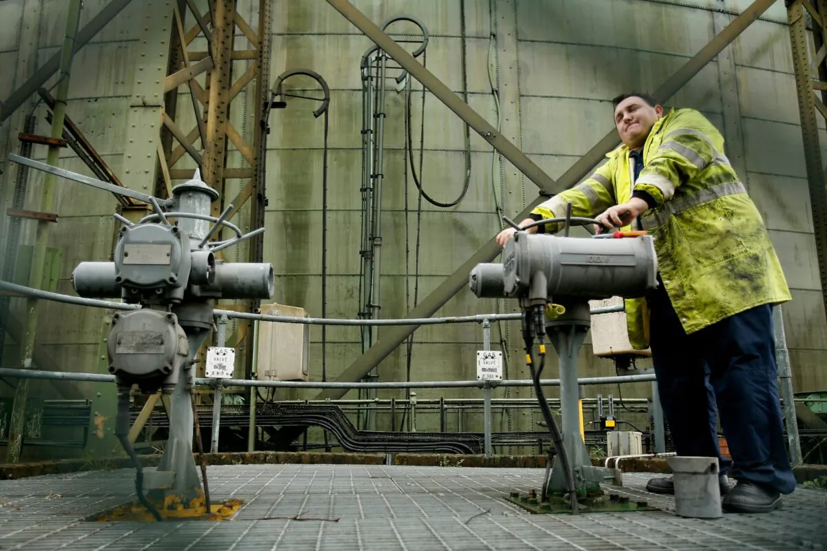 A worker attempts to open a gas valve below the structure of a gas storage tank in London on Oct. 10, 2006. (Daniel Berehulak/Getty Images)