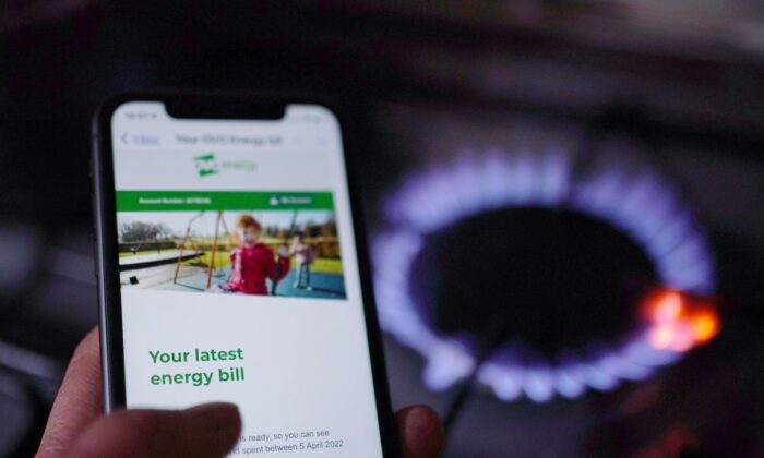 A household energy bill displayed on a mobile phone held next to a gas hob, in a file photo dated Aug. 25, 2022. (Yui Mok/PA Media)