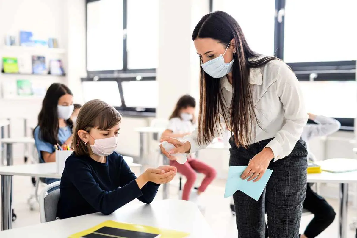 Jason Clare, Minister for Education and Youth of Australia, recently announced priority visas for overseas teachers to ease the teacher shortage Australia faces. This picture shows a teacher spraying students with hand sanitiser. (Shutterstock image)
