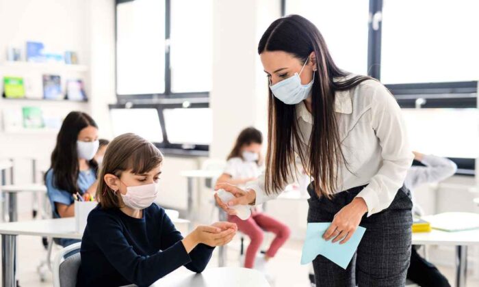 Jason Clare, Minister for Education and Youth of Australia, recently announced priority visas for overseas teachers to ease the teacher shortage Australia faces. This picture shows a teacher spraying students with hand sanitiser. (Shutterstock image)
