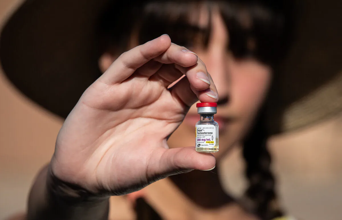 A "detransitioner" who regrets surgically removing her breasts as a teen in an effort to live more like a boy, holds testosterone medication used by transgender patients on Aug. 26, 2022. (John Fredricks/The Epoch Times)