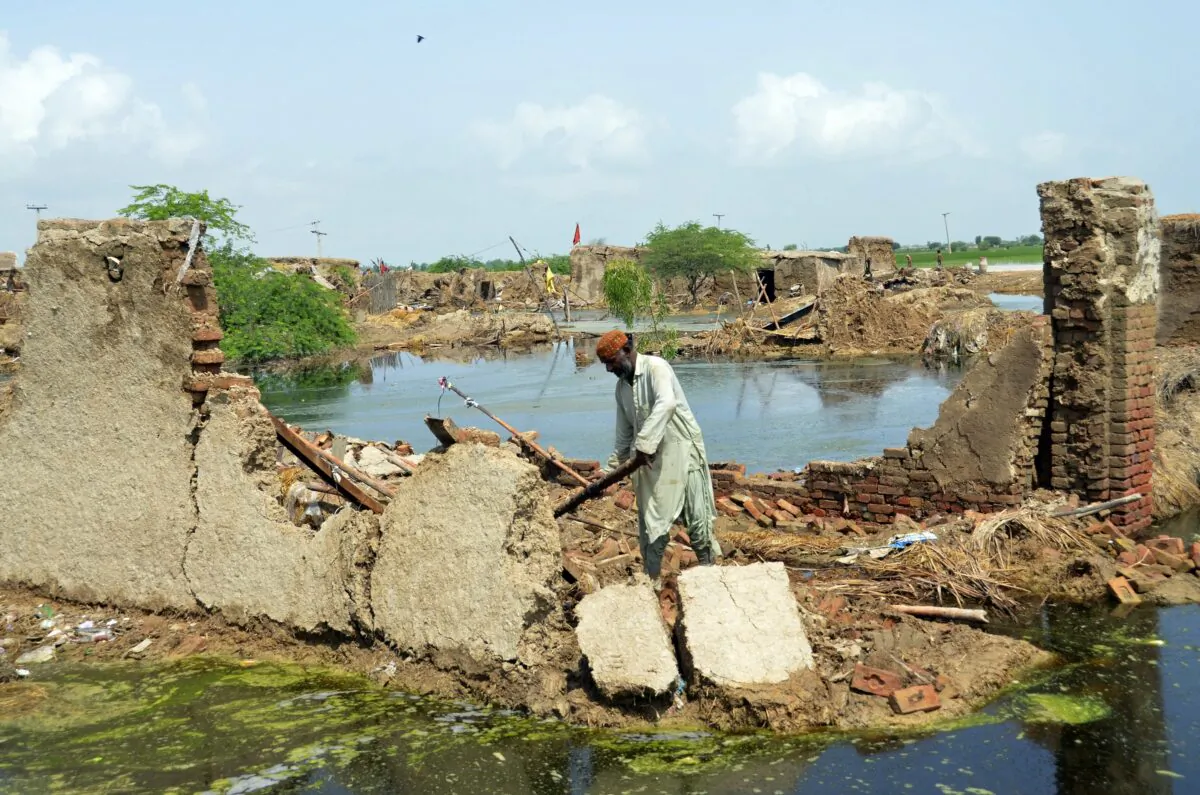 A man looks for salvageable belongings from his flood-hit home surrounded by water in Jaffarabad, a district of Pakistan's southwestern Baluchistan province, on Aug. 28, 2022. (Zahid Hussain/AP Photo)