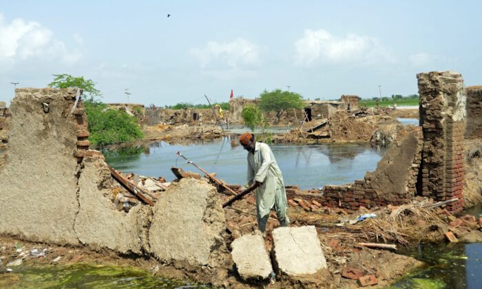 A man looks for salvageable belongings from his flood-hit home surrounded by water in Jaffarabad, a district of Pakistan's southwestern Baluchistan province, on Aug. 28, 2022. (Zahid Hussain/AP Photo)