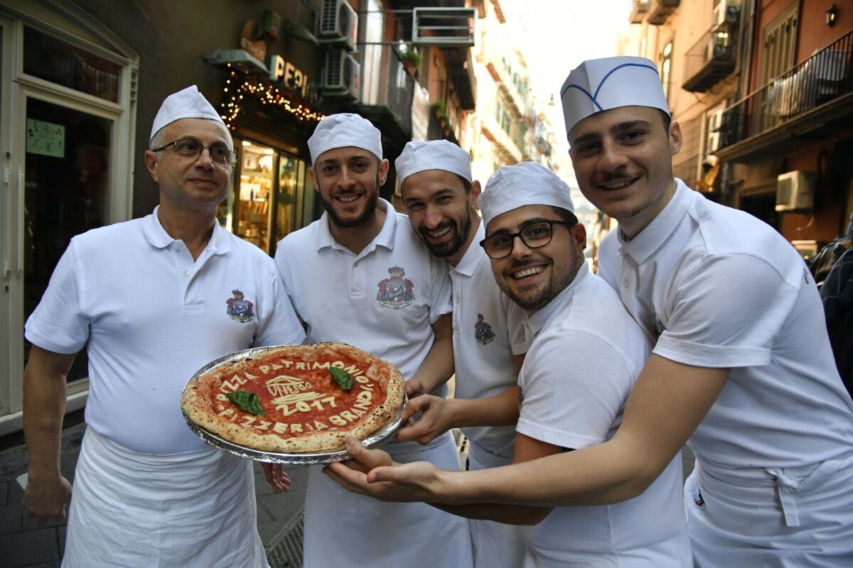 Neapolitan pizza makers pose with a pizza celebrating the UNESCO decision to make the art of Neapolitan "Pizzaiuolo" an "intangible heritage" on Dec. 7, 2017, outside Pizzeria Brandi in Naples. (TIZIANA FABI/AFP via Getty Images)