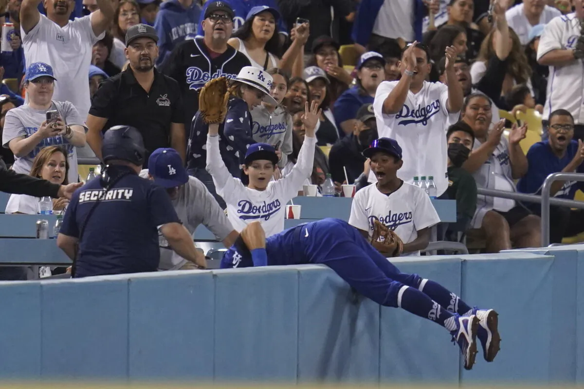 Los Angeles Dodgers left fielder Chris Taylor (3) falls in to the stands while catching a foul ball hit by Milwaukee Brewers' Omar Narvaez during the fifth inning of a baseball game in Los Angeles, Aug. 22, 2022. (Ashley Landis/AP Photo)
