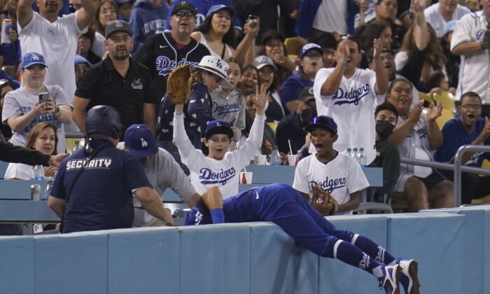 Los Angeles Dodgers left fielder Chris Taylor (3) falls in to the stands while catching a foul ball hit by Milwaukee Brewers' Omar Narvaez during the fifth inning of a baseball game in Los Angeles, Aug. 22, 2022. (Ashley Landis/AP Photo)
