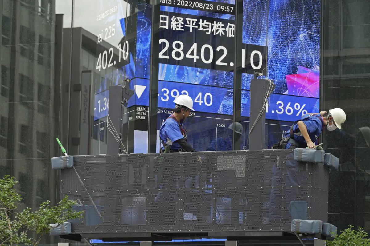 Window cleaners prepare their work in front of an electronic stock board showing Japan's Nikkei Index at a securities firm, on Aug. 23, 2022, in Tokyo. Asian shares traded lower that day, echoing a broad sell-off on Wall Street amid speculation about another interest rate raise from the U.S. Federal Reserve. (AP Photo/Eugene Hoshiko)
