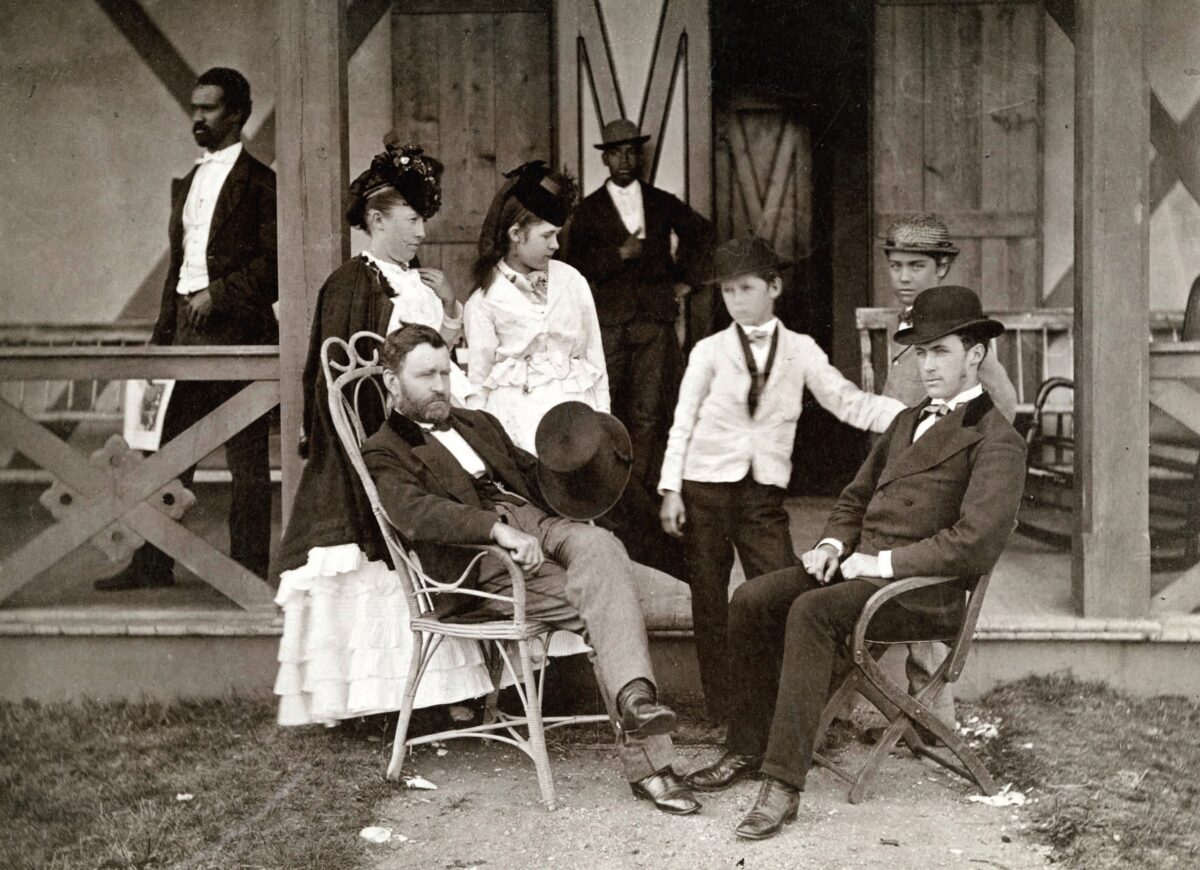 Ulysses
Grant (seated
left), Julia Dent
Grant (standing,
leftmost), and their
four children, Jesse,
Ulysses Jr., Nellie,
and Frederick, in
front of their cottage
in Long Branch, N.J.,
1870. The identities
of the men in the
background are
unknown. (Public domain)