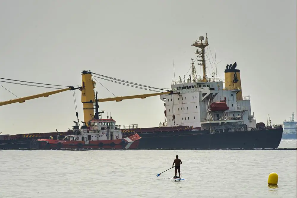 A man approaches with his paddle surf board to get a closer look at the Tuvalu-registered OS 35 cargo ship lying on the seabed, offshore Gibraltar, on 30 Aug. 2022. (Marcos Moreno/AP)
