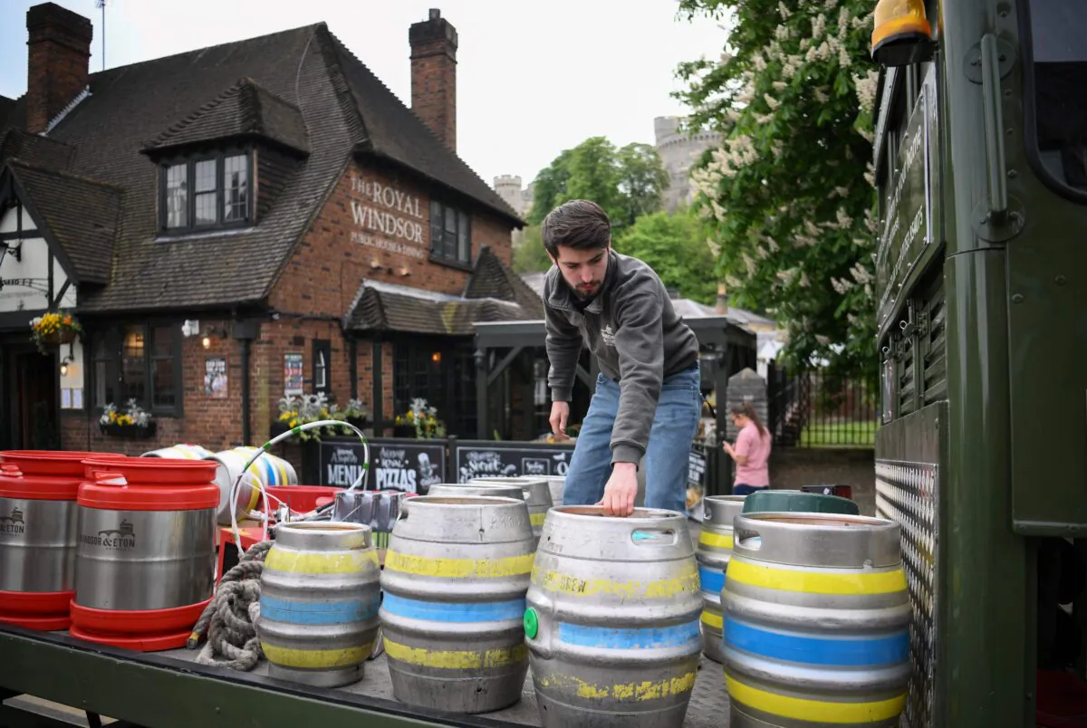 A workers picks up draft barrels of beer from a horse-drawn delivers to a pub in Windsor, England, on April 28, 2022. (Daniel Leal/AFP via Getty Images)