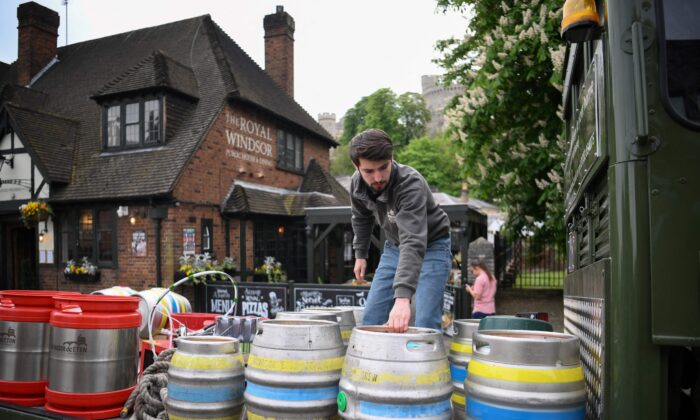 A workers picks up draft barrels of beer from a horse-drawn delivers to a pub in Windsor, England, on April 28, 2022. (Daniel Leal/AFP via Getty Images)
