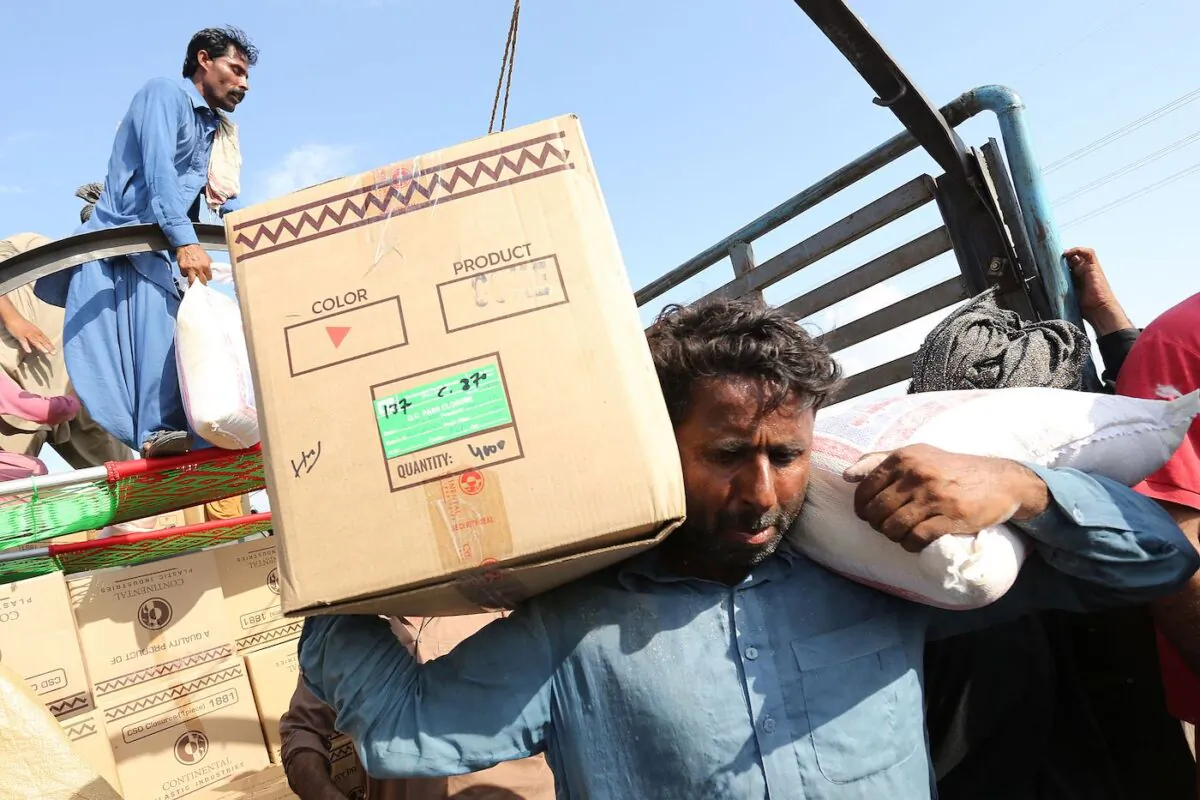 A displaced man carries relief food box in a flood hit area following heavy monsoon rains in Dera Ghazi Khan district of Punjab province on Aug. 29, 2022. (Shahid Saeed Mirza/AFP via Getty Images)