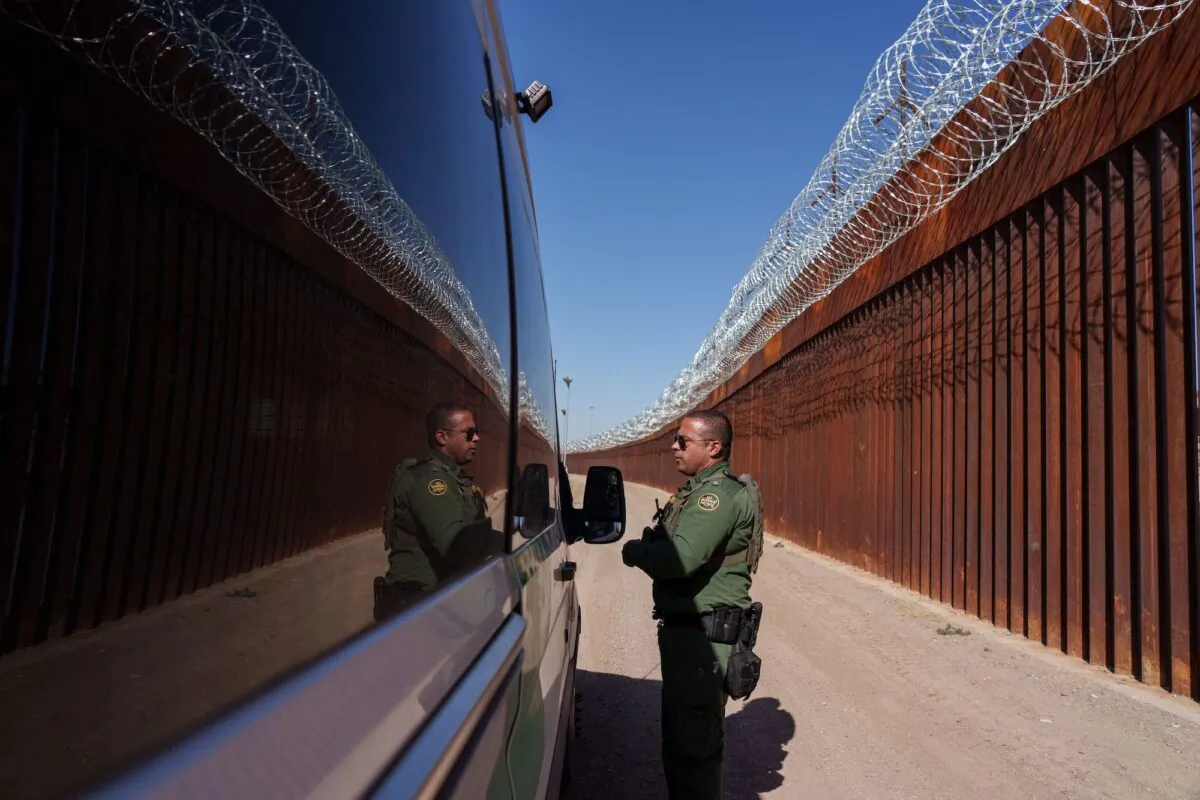 U.S. Border Patrol agent Carlos Rivera is reflected in the window of a vehicle as he speaks to another agent along the border wall in downtown El Paso, Texas, on June 3, 2022. (Paul Ratje/AFP via Getty Images)