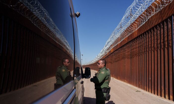 U.S. Border Patrol agent Carlos Rivera is reflected in the window of a vehicle as he speaks to another agent along the border wall in downtown El Paso, Texas, on June 3, 2022. (Paul Ratje/AFP via Getty Images)