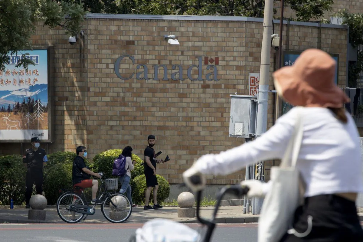 A security guard stands on duty as residents pass by the Canadian Embassy in Beijing on June 19, 2020. (The Canadian Press/AP-Ng Han Guan)