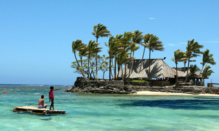 2003 年 11 月 11 日，美拉尼西亚儿童漂浮在度假村云集的斐济珊瑚海岸的竹浮桥上。（Torsten Blackwood/法新社来自 Getty Images）