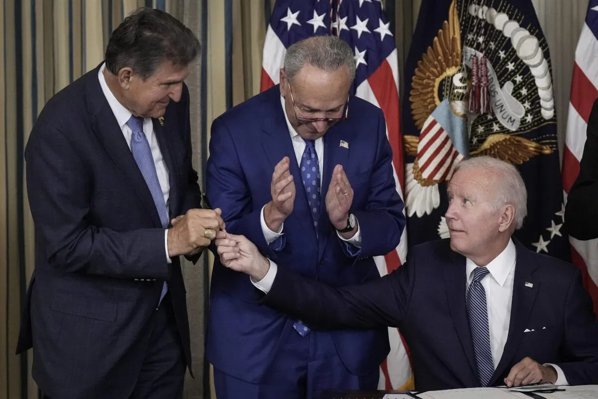 With Senate Majority Leader Charles Schumer (D-N.Y.) looking on, President Joe Biden hands Sen. Joe Manchin (D-W.Va.) the pen he used to sign into law the so-called Inflation Reduction Act, or Schumer-Manchin bill, at the White House on Aug. 16, 2022.( Drew Angerer/Getty Images)