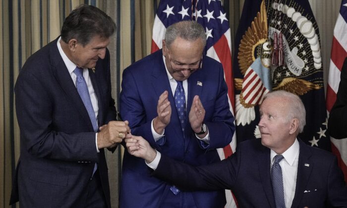 With Senate Majority Leader Charles Schumer (D-N.Y.) looking on, President Joe Biden hands Sen. Joe Manchin (D-W.Va.) the pen he used to sign into law the so-called Inflation Reduction Act at the White House on Aug. 16. The law devotes hundreds of billions of dollars to fostering “green” energy, but many forms of it ironically will have adverse effects on the environment. (Drew Angerer/Getty Images)