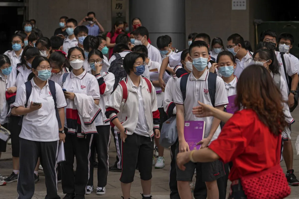 A volunteer directs students as they wait to enter a school for the first day of China's national college entrance examinations, in Beijing on June 7, 2022. (Andy Wong/AP Photo)