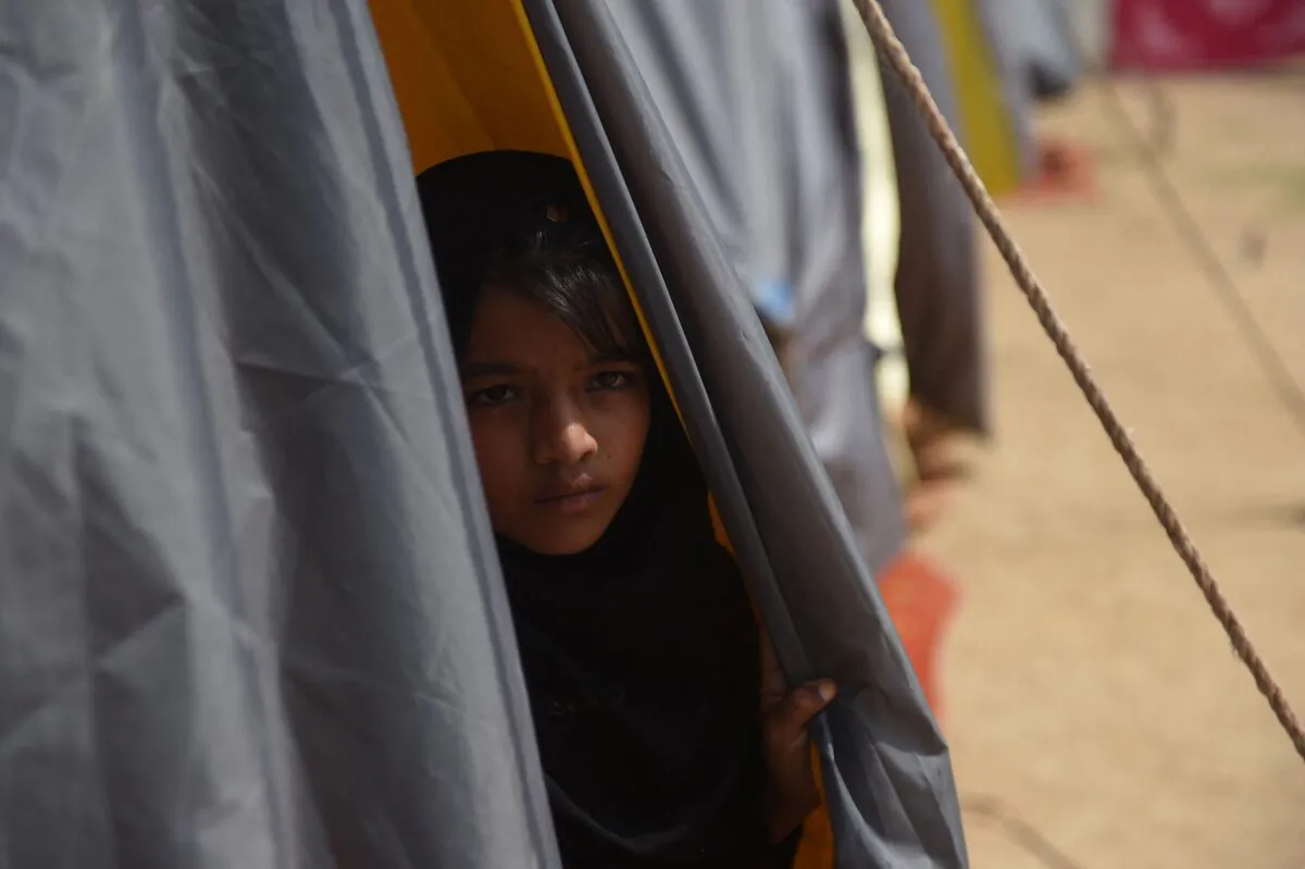 An internally displaced flood-affected girl looks out from a tent at a makeshift camp of the Alkhidmat Foundation Pakistan in Karachi, Pakistan, on Sept. 6, 2022. (Rizwan Tabassum/AFP via Getty Images)