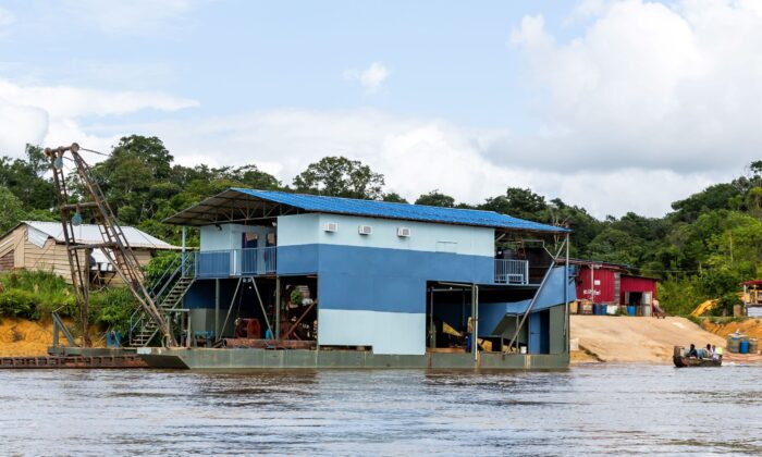 A boat sails by a free-service shop along the Maroni river on the Suriname coast side, on Jan. 20, 2019. (Jody Amiet/AFP via Getty Images)