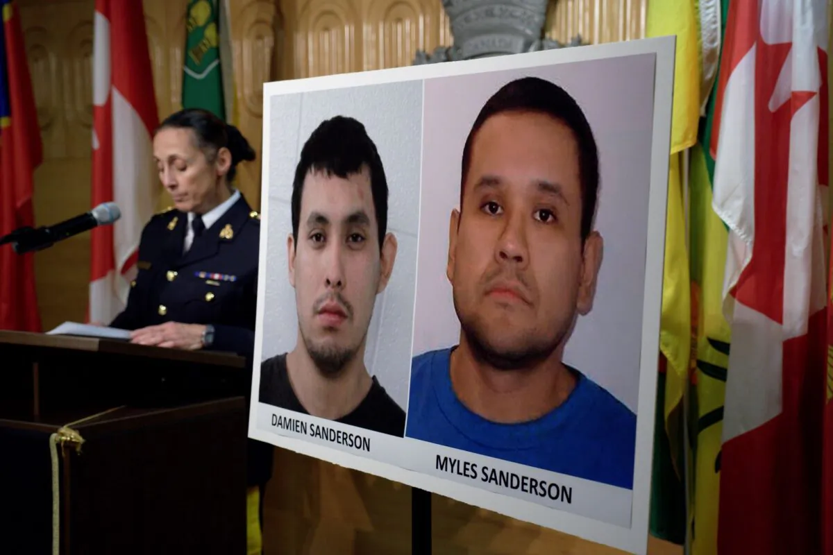 RCMP Assistant Commissioner Rhonda Blackmore speaks during a press conference at RCMP F Division Headquarters in Regina on Sept. 4, 2022, while a sign displays images of suspects Damien Sanderson (L) and Myles Sanderson. (The Canadian Press/Michael Bell)