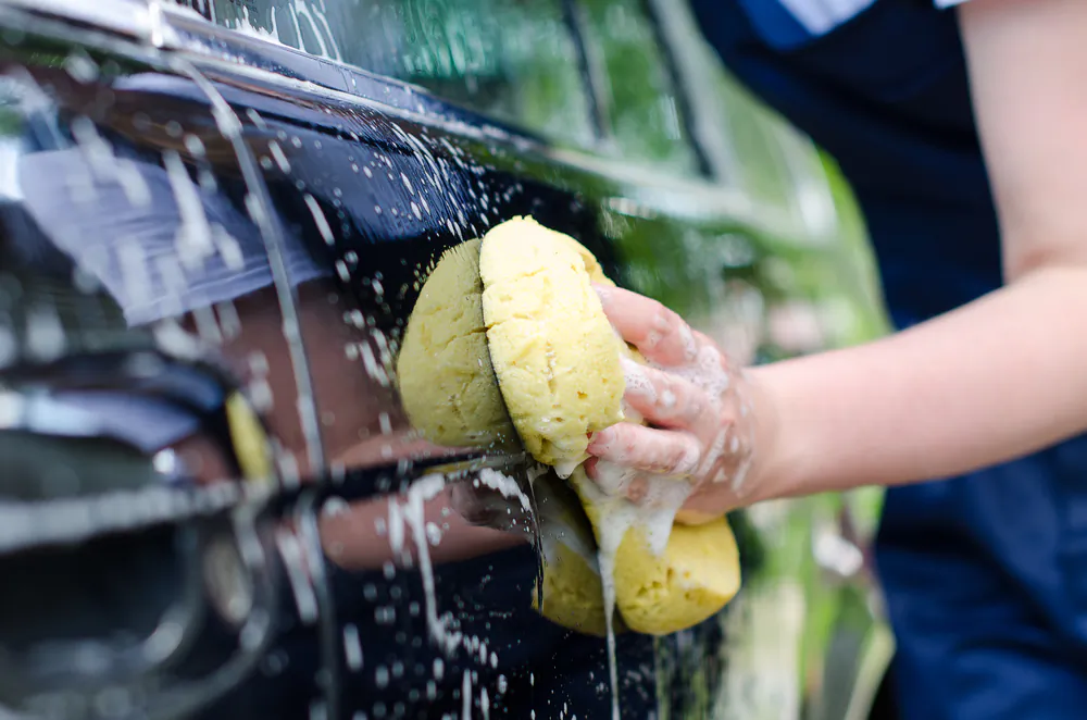 Wash the car in small sections, rinsing immediately to help prevent soapy residue from drying and forming streaks. (M-Production/Shutterstock)