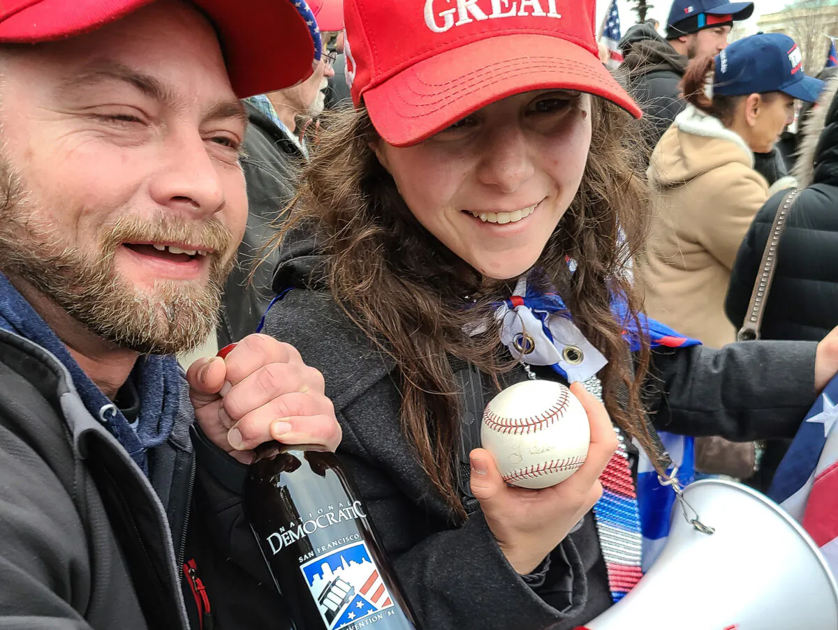Megan Paradise and an unidentified man pose on the east steps of the U.S. Capitol with items taken from House Speaker Nancy Pelosi's office on Jan. 6, 2021. (Scott Wheeler)