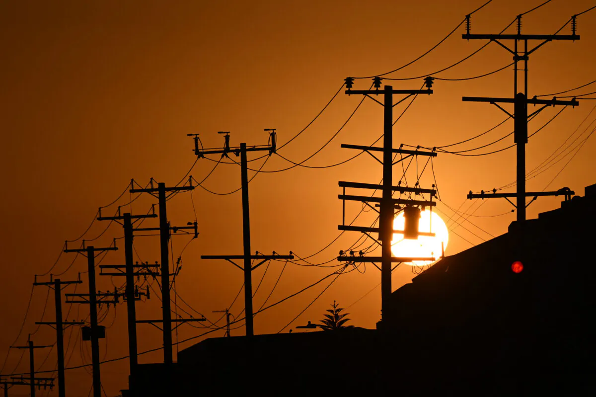 The sun sets behind power lines near homes during a heat wave in Los Angeles on Sept. 6, 2022. (Patrick T. Fallon/AFP via Getty Images)