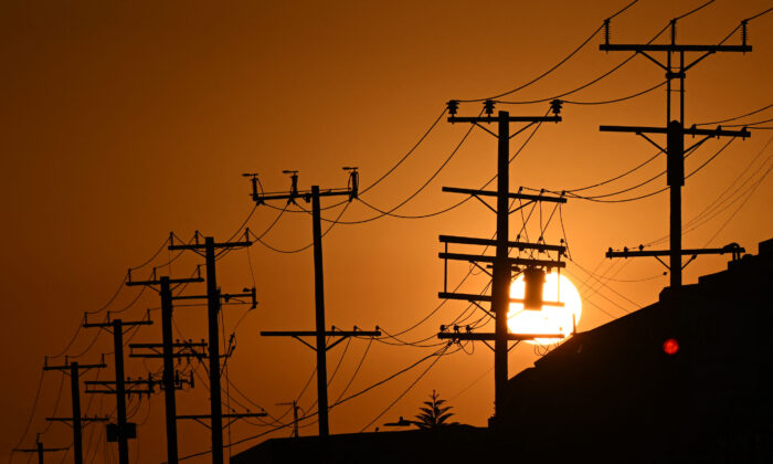 The sun sets behind power lines near homes during a heat wave in Los Angeles on Sept. 6, 2022. (Patrick T. Fallon/AFP via Getty Images)