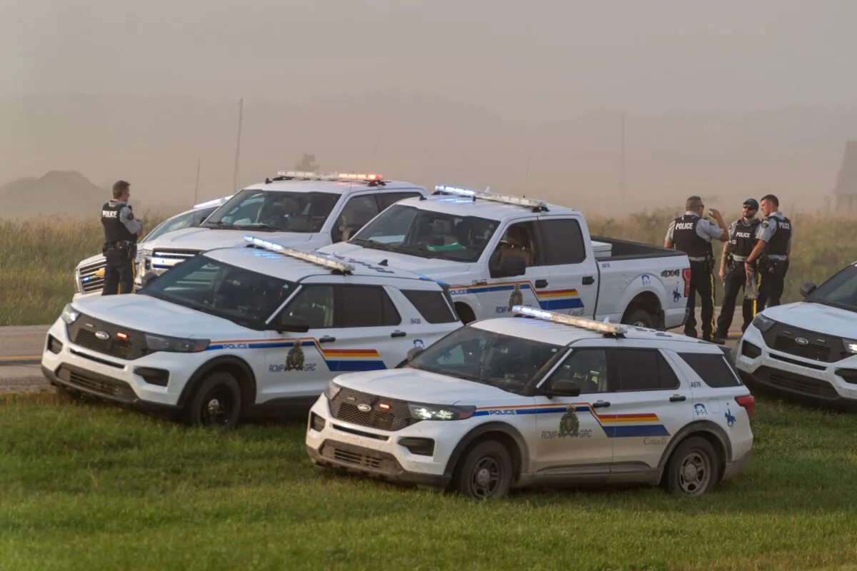 Police and investigators are seen at the side of the road outside Rosthern, Sask., where a suspect of the Sept. 4 stabbing attacks was arrested, on Sept. 7, 2022. (The Canadian Press/Heywood Yu)