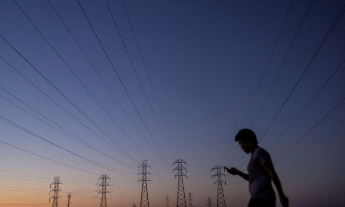 A man walks by power lines, as California's grid operator urged the state's 40 million people to ratchet down the use of electricity in homes and businesses as a heat wave settled over much of the state, in Mountain View, Calif., on Aug. 17, 2022. (Carlos Barria/Reuters)