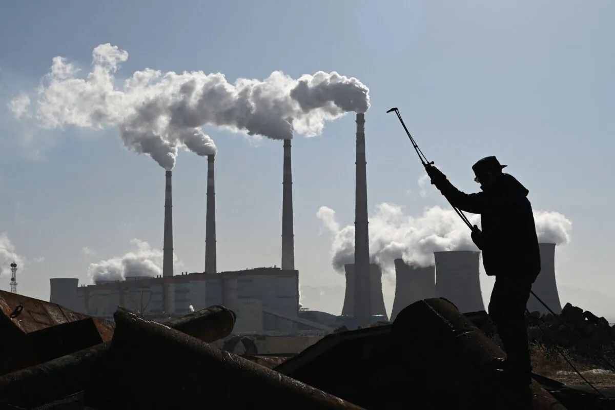A worker uses a torch to cut steel pipes near the coal-powered Datang International Zhangjiakou Power Station at Zhangjiakou, in China's northern Hebei Province on Nov. 12, 2021. (Greg Baker/AFP via Getty Images)